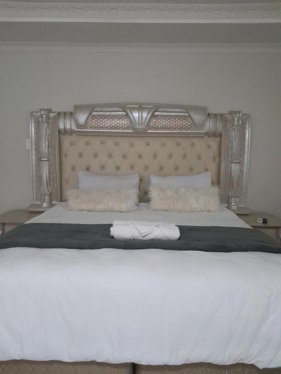 ein Schlafzimmer mit einem großen Bett mit weißer Bettwäsche und Kissen in der Unterkunft Rest Camp Lodge in Manzini