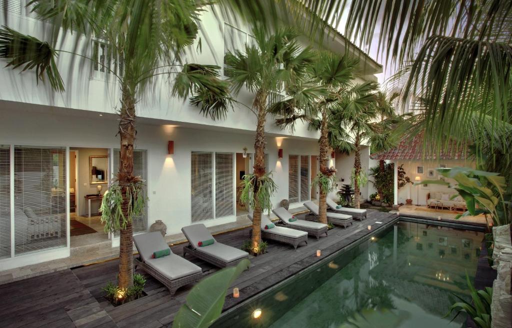 una piscina del complejo con palmeras y tumbonas en Room & Vespa 4, en Seminyak