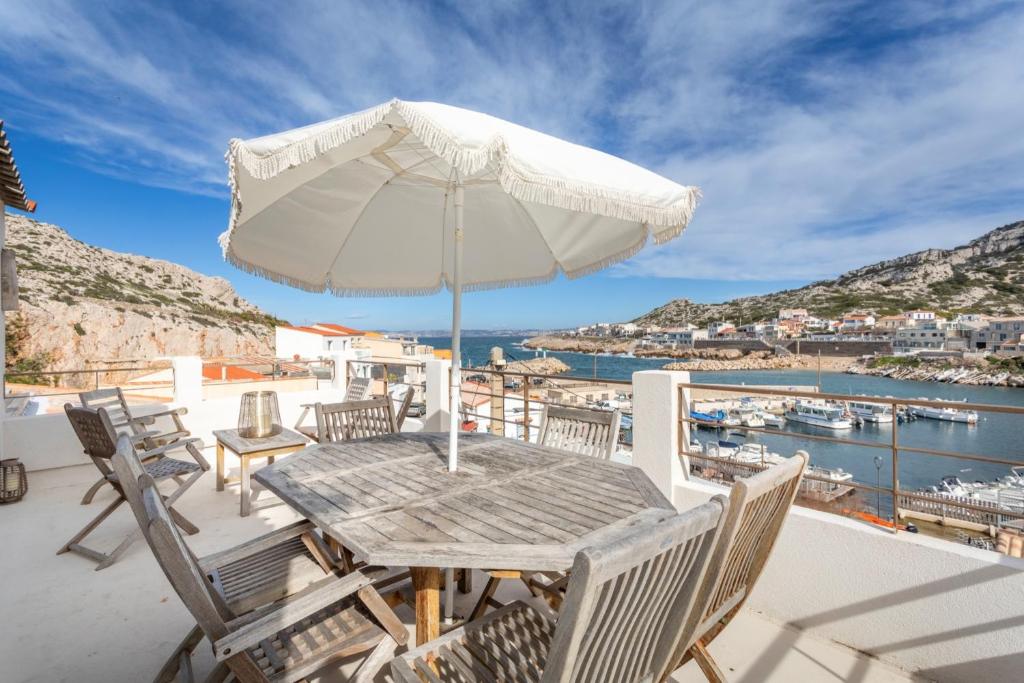 une table en bois avec un parasol sur un balcon dans l'établissement Mars is Goudes * Bord de mer * Luxe * Confort, à Marseille