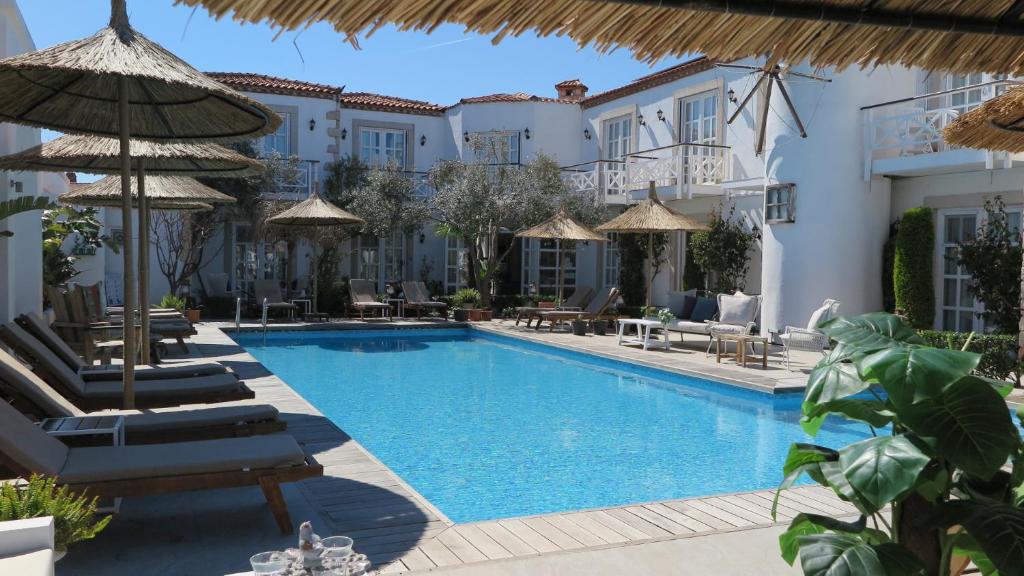 a pool at a hotel with chairs and umbrellas at Bay C in Alacati