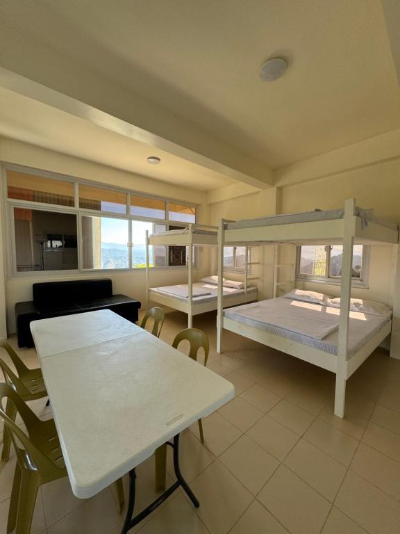 2 Etagenbetten in einem Zimmer mit einem Tisch und Stühlen in der Unterkunft Mountain view baguio-itogon in Itogon