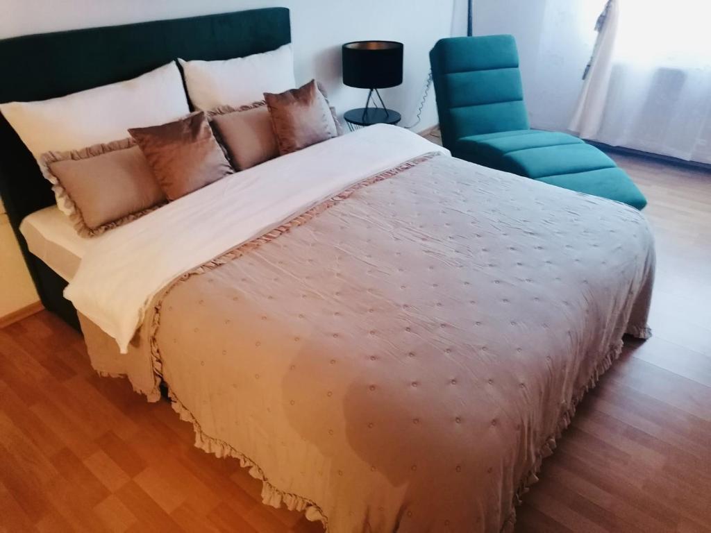 a bedroom with a large bed and a blue chair at 7.Nebo/ Spa apartman Vinkovci in Vinkovci