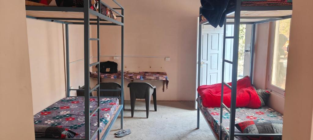 a room with two bunk beds and a desk at Saanidhya hostels in Mukteswar