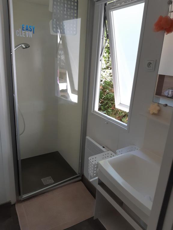 uma casa de banho com um chuveiro, um lavatório e um espelho. em Mobil-home a louer dans un camping **** proche de la mer et forêt em Saint-Jean-de-Monts