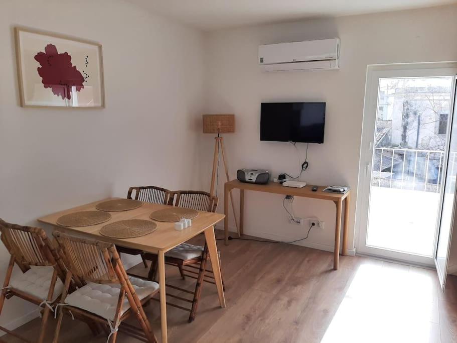 a dining room with a table and chairs and a television at River & Beach Apartment near Lisbon in Trafaria
