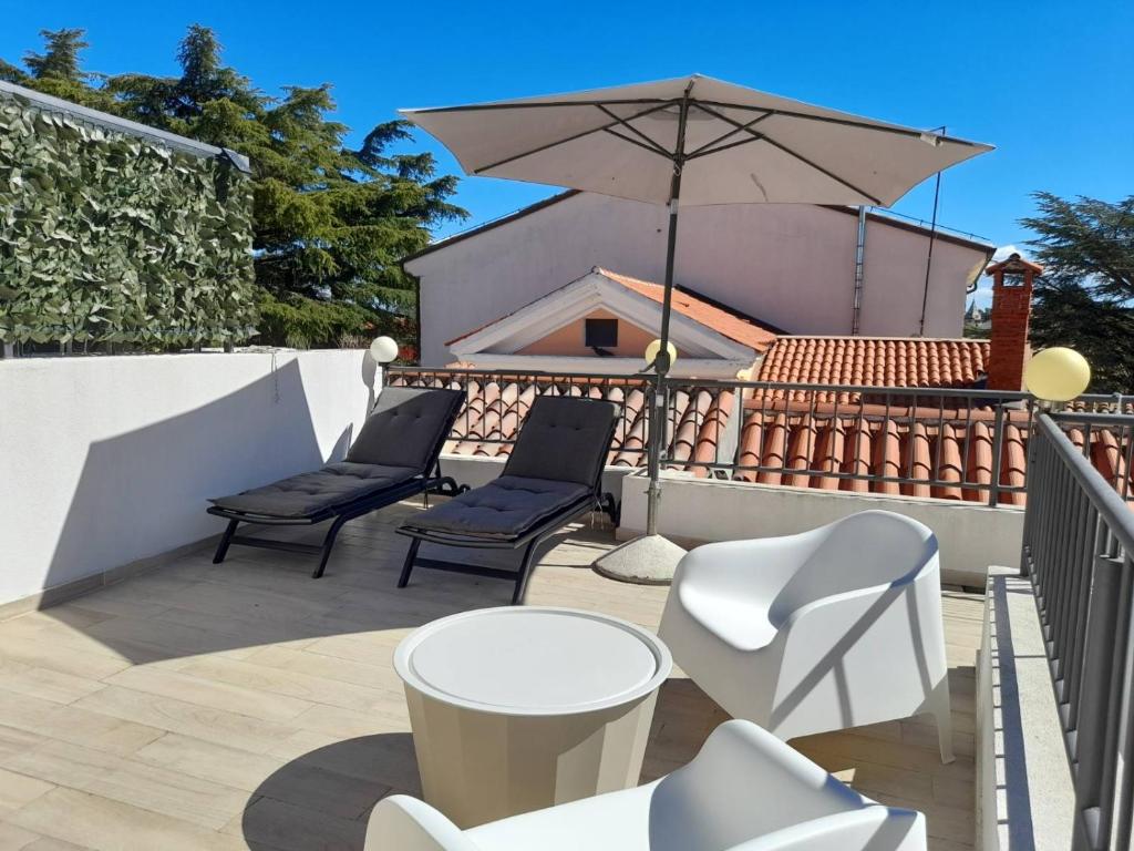 a patio with two chairs and an umbrella at App Hedonist in Novigrad Istria