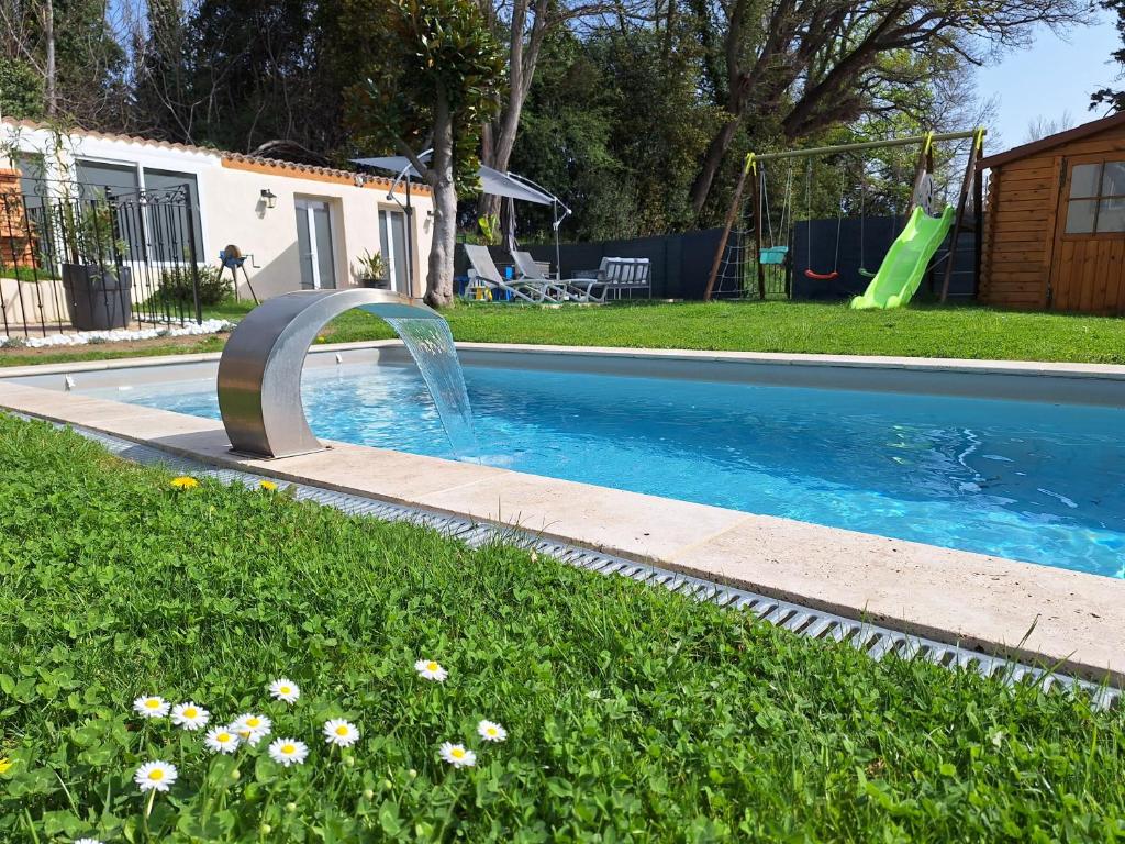 una piscina con una fuente de agua en un patio en La Maison du Moulin de Tartay en Aviñón