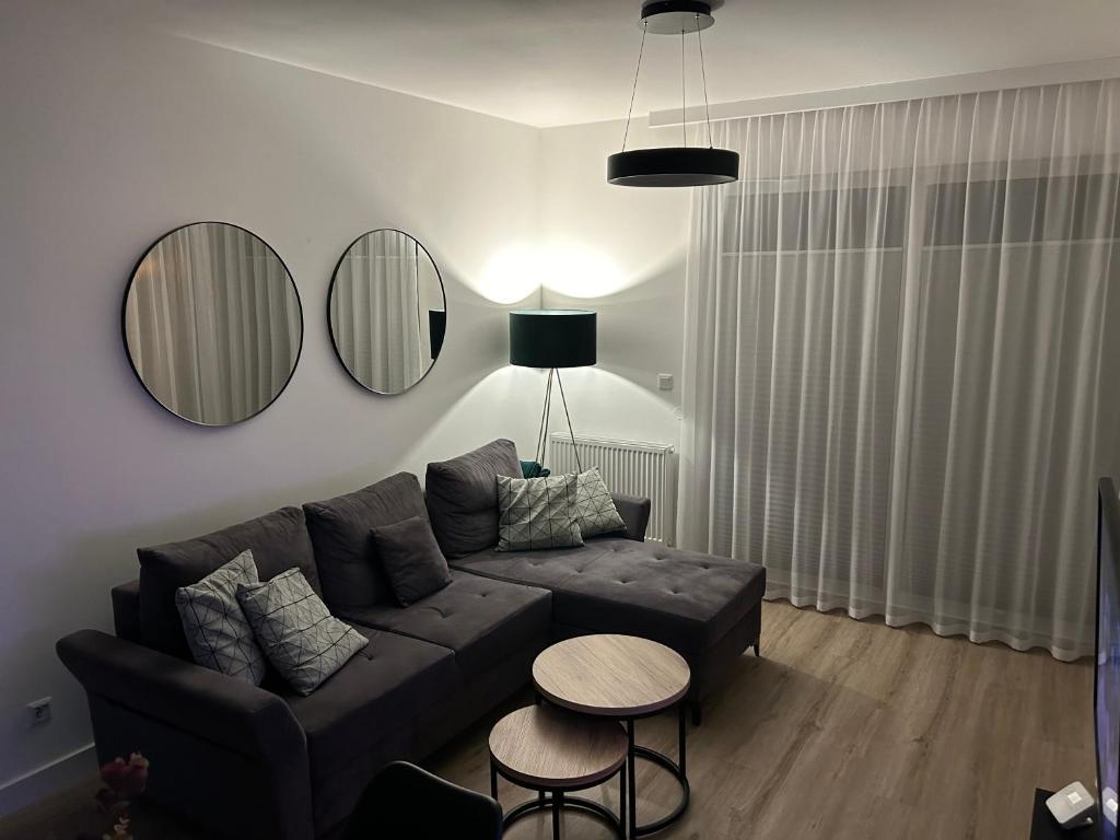 sala de estar con sofá y 2 espejos en Apartament Sosnowa 4, en Mielno