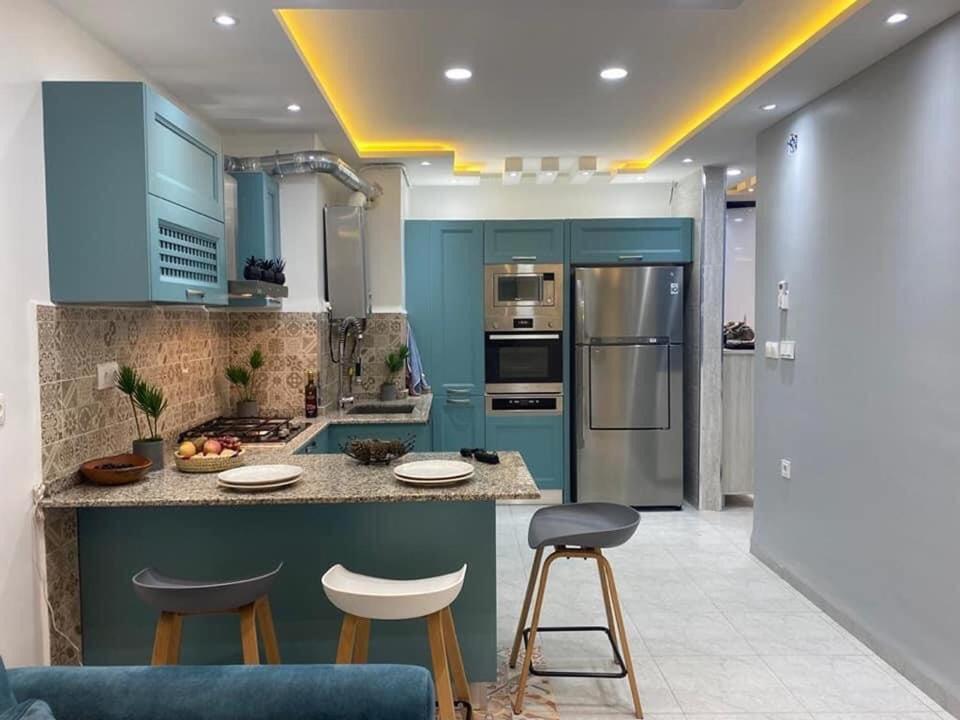 a kitchen with blue cabinets and bar stools at Appartement pour vacances in Boumerdes