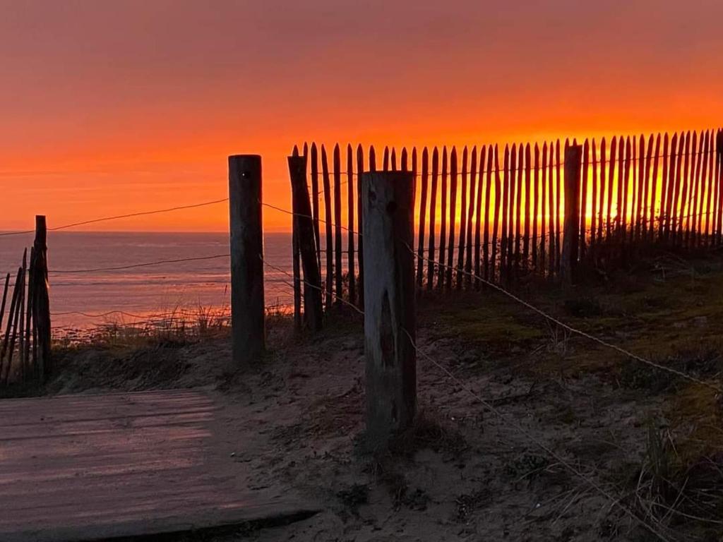 une clôture sur la plage avec un coucher de soleil en arrière-plan dans l'établissement Mon coin de Paradis, à Saint-Jean-de-Monts
