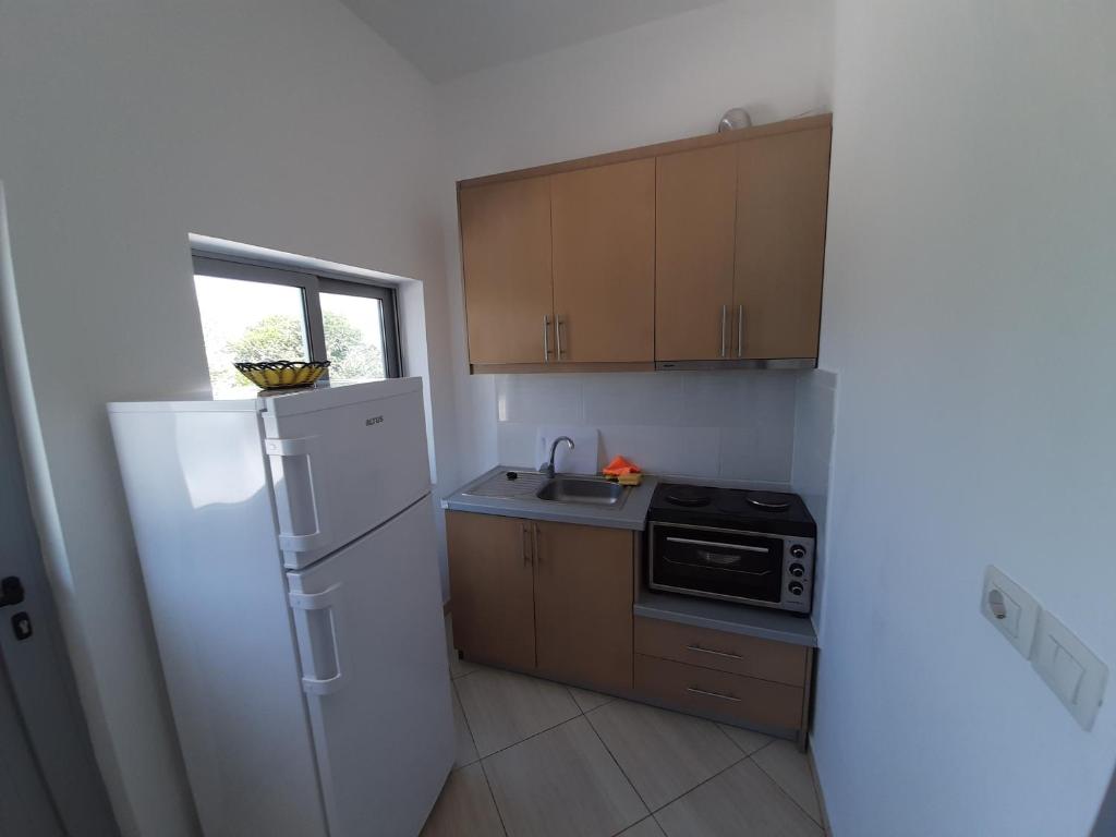 a small kitchen with a refrigerator and a sink at Villas Ermali in Ksamil