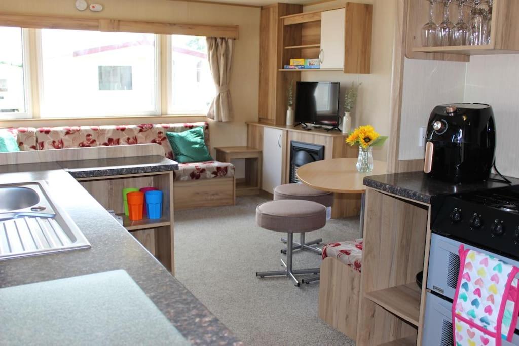 Norfolk broads caravan sleeps 8 في Belton: مطبخ وغرفة معيشة مع طاولة وكرسي