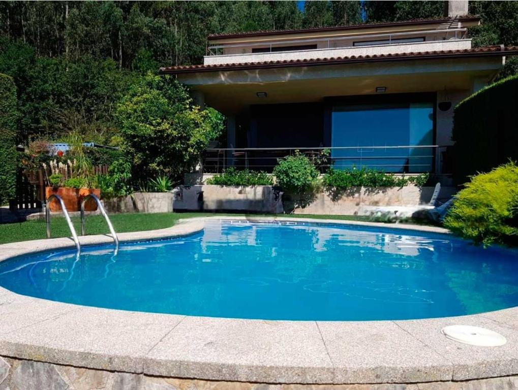 a swimming pool with a fountain in front of a house at Casa con piscina Sanxenxo in Pontevedra