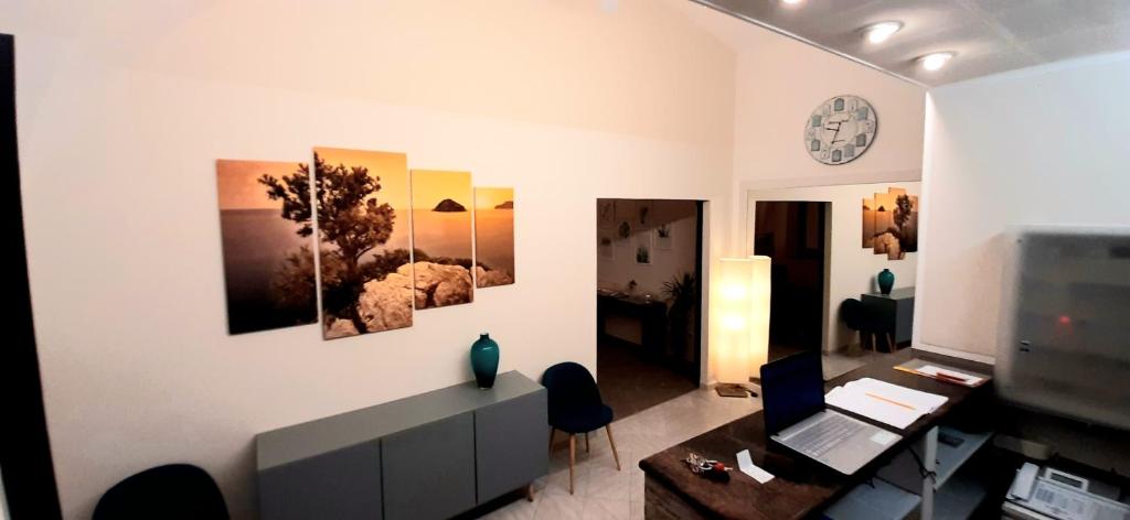 a living room with a desk and a clock on the wall at HOTEL MALIBU in Spotorno