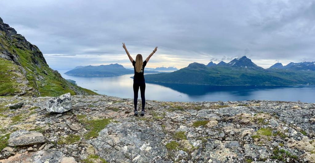 a person standing on top of a mountain with their arms up at Artic Dream in Gratangen
