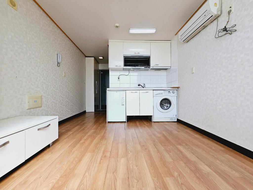uma cozinha com máquina de lavar e secar roupa num quarto em D&D PineVill em Busan
