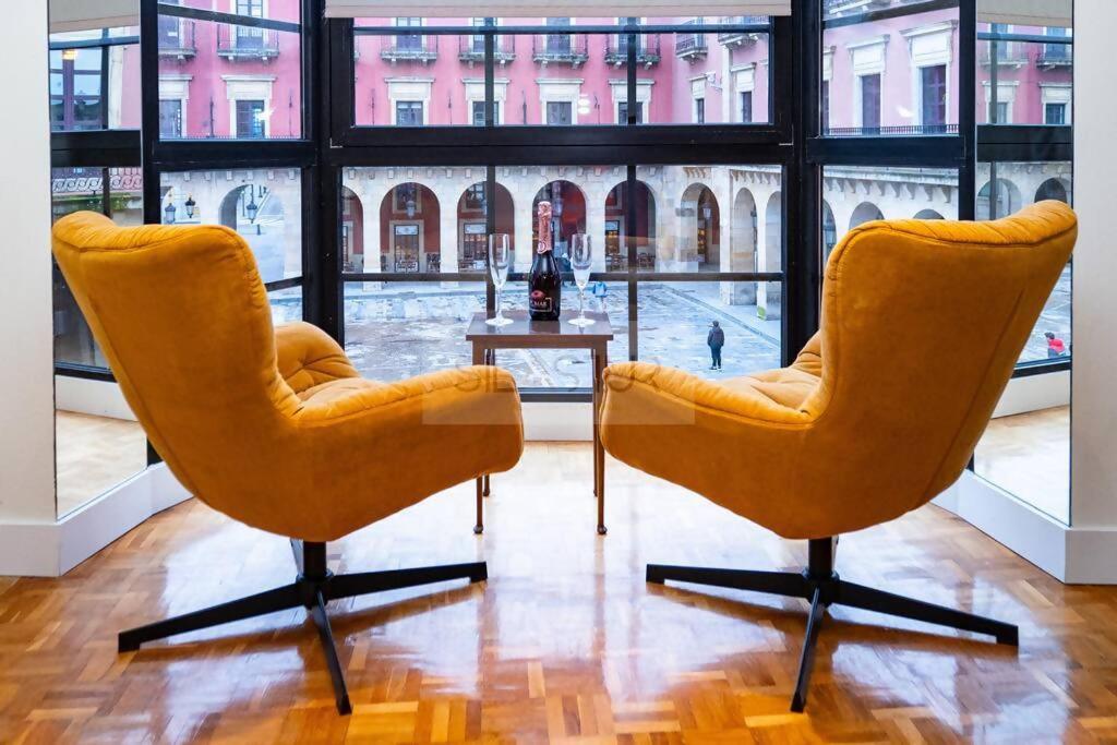 2 stoelen en een tafel in een kamer met een groot raam bij Anne Apartamento in Gijón