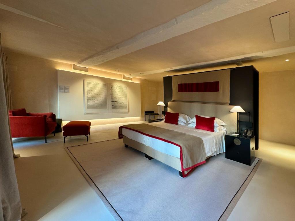um quarto com uma cama grande e uma cadeira vermelha em Hotel Palazzo Durazzo Suites em Gênova