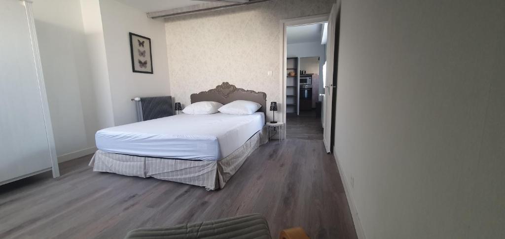 een slaapkamer met een bed met witte lakens en houten vloeren bij Villa Argentine T2 classé 2* thème cosy in Dax