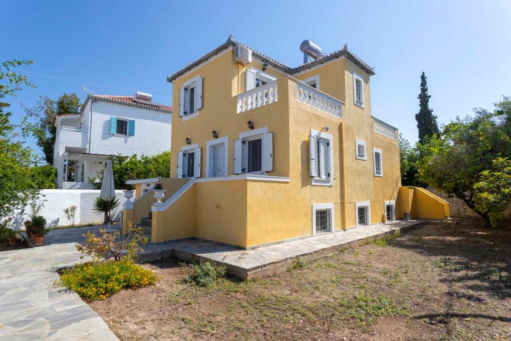 a large yellow house with a yard in front of it at Villa Santa Marina in Spetses