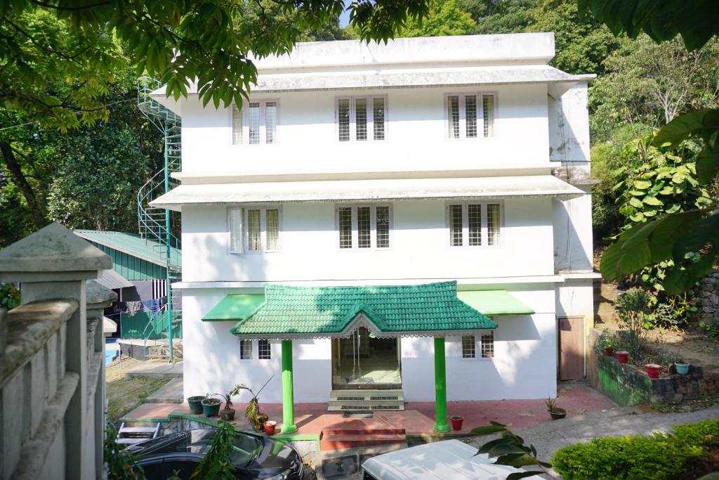 ein weißes Gebäude mit grünem Dach in der Unterkunft Classiyo Green Mount Resort in Chinnakanal