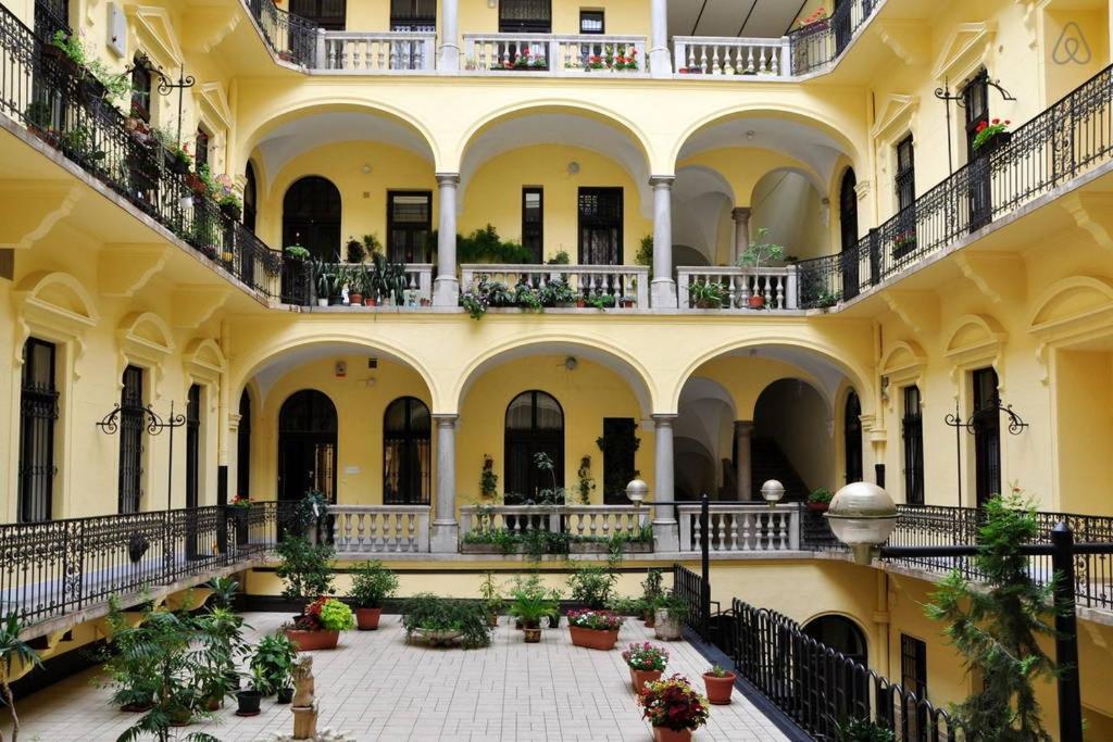 a large building with balconies and a courtyard with potted plants at Charming Art Deco Flat in Budapest