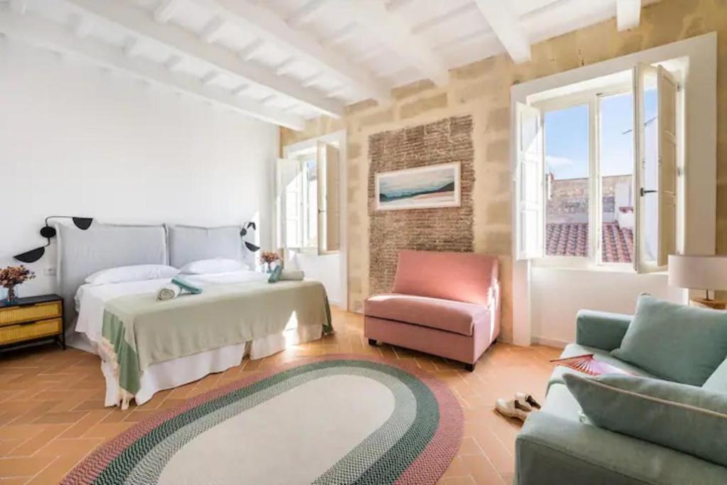 a bedroom with a bed and a couch and a chair at Suite 3 in Mahón
