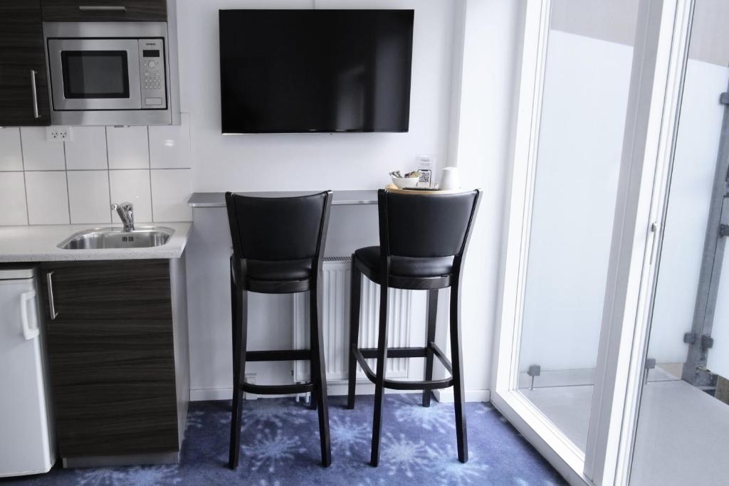 two black bar stools in a kitchen with a microwave at ApartHotel Faber in Aarhus