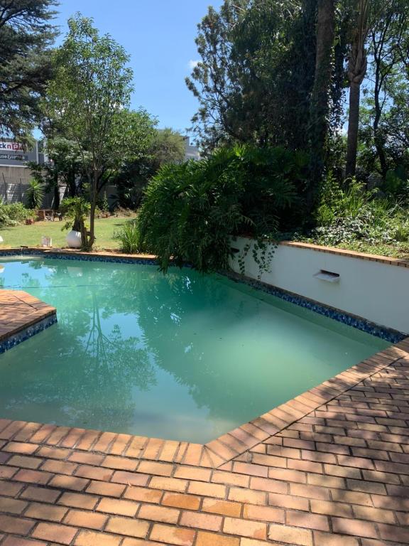 a swimming pool with green water in a yard at Urban Fourways Haven in Sandton