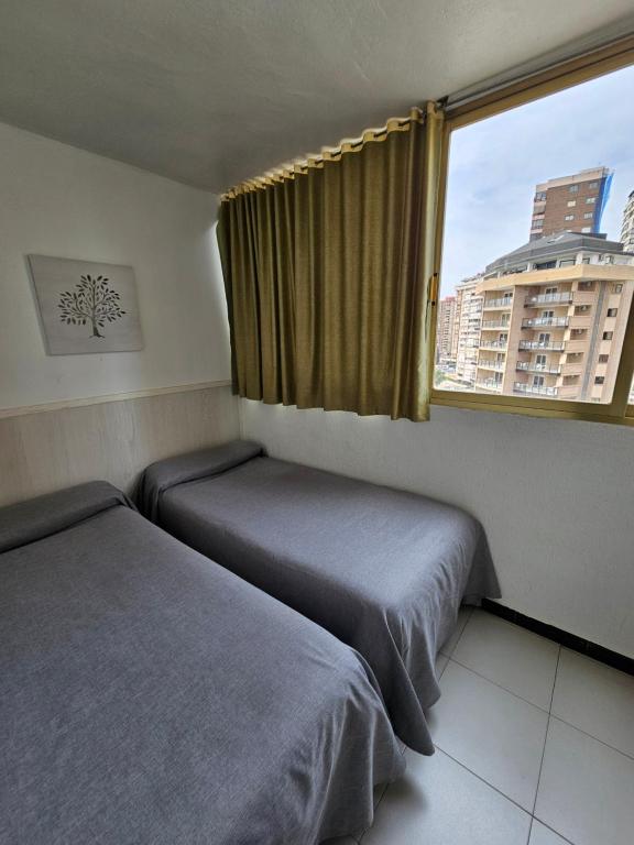 a hotel room with two beds and a window at Apartamentos Maria Victoria in Benidorm