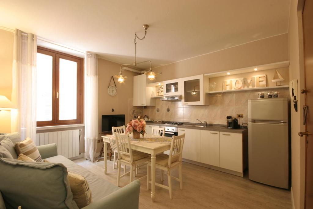 eine Küche und ein Wohnzimmer mit einem Tisch und einem Kühlschrank in der Unterkunft Violetta Maison, elegante e romantica a Salo’ in Salò