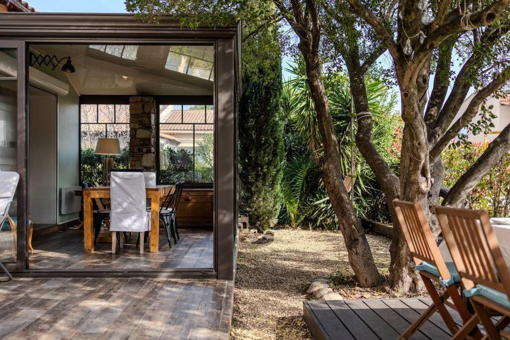 une porte en verre menant à une terrasse avec une table et des chaises. dans l'établissement Superbe maison élégante proche mer, au Pradet