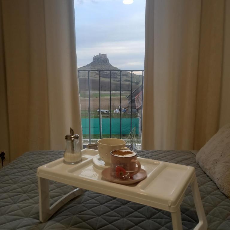 a tray with a cup of coffee on a bed with a window at Apartmán s výhľadom na Spišský Hrad in Studenec
