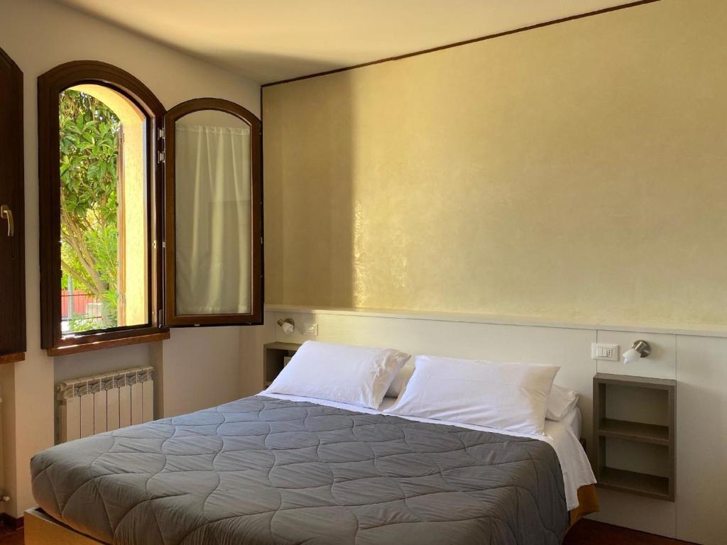 sypialnia z łóżkiem i 2 oknami w obiekcie Unabhaengige Wohnung in Sirmione mit Eigener Terrasse w Sirmione