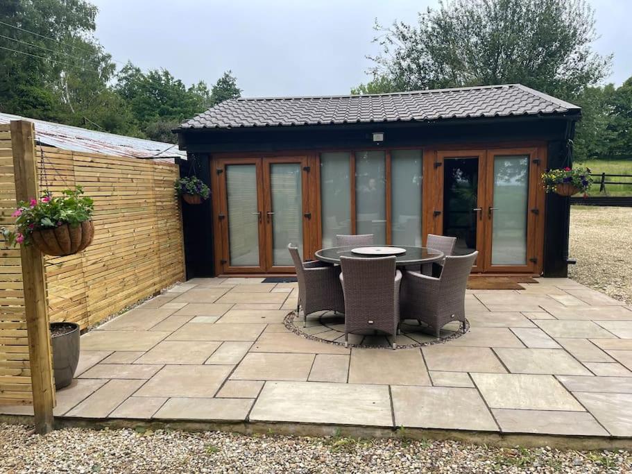 a patio with a table and chairs in front of a building at Converted barn one bedroom studio glamping in Horspath