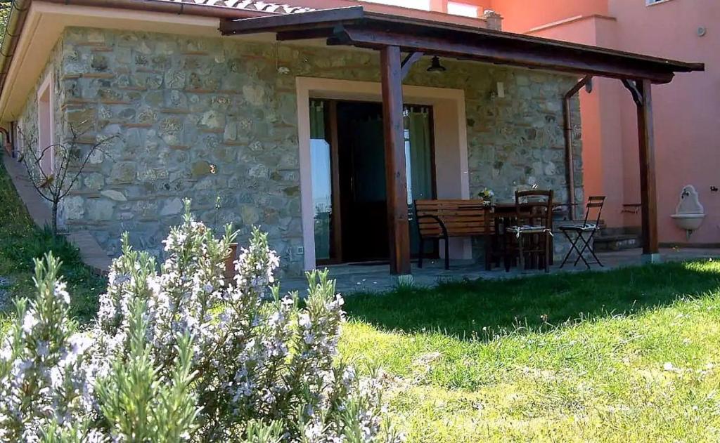 a stone house with a patio with a table and chairs at Casa Roberto - Campagna Toscana vicino al mare in Castellina Marittima