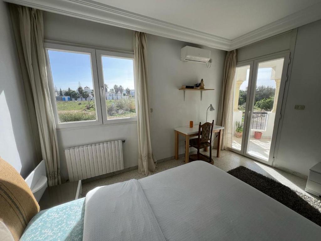a bedroom with a bed and a desk and windows at appartement 14 in Chott Meriem