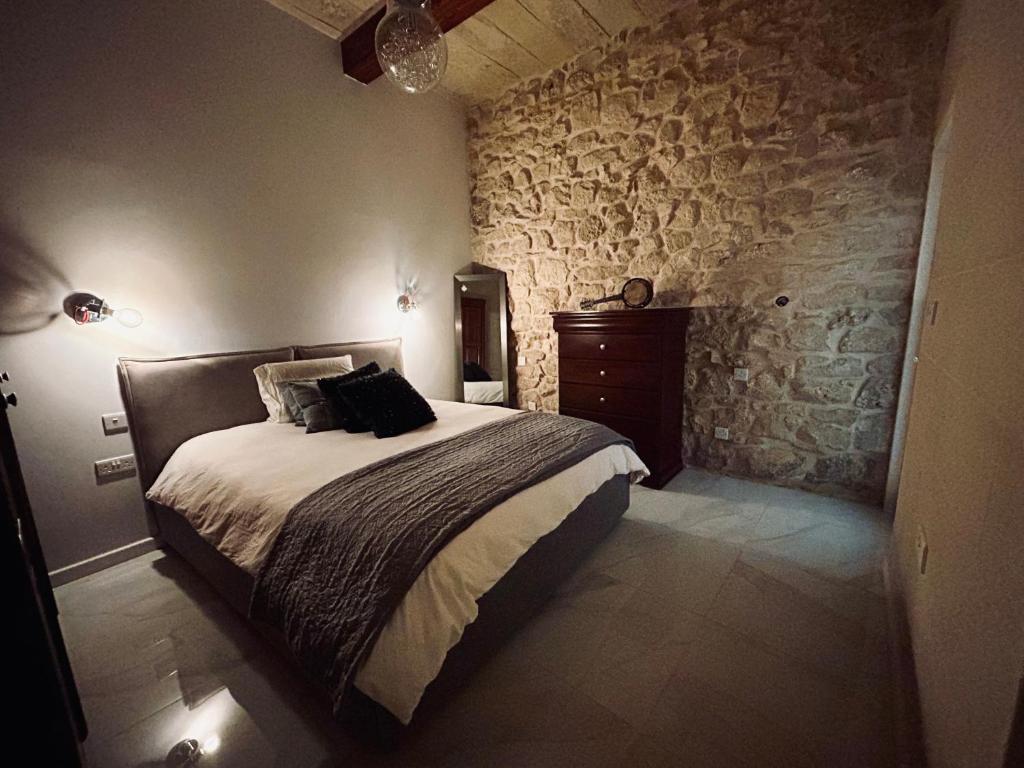 1 dormitorio con cama y pared de piedra en Ta Pietru, en Żabbar