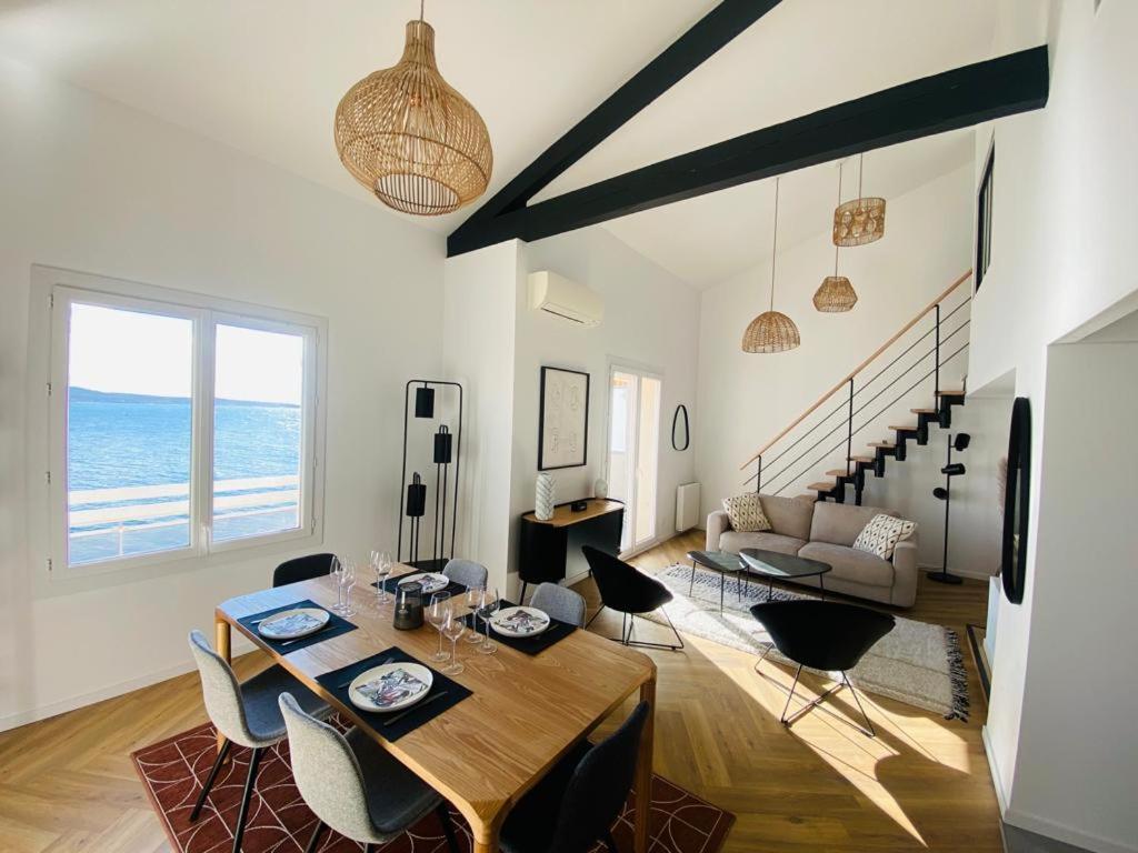 ein Wohnzimmer mit einem Tisch, Stühlen und Meerblick in der Unterkunft Magnifique duplex vue mer inoubliable Sanary Sur Mer in Sanary-sur-Mer