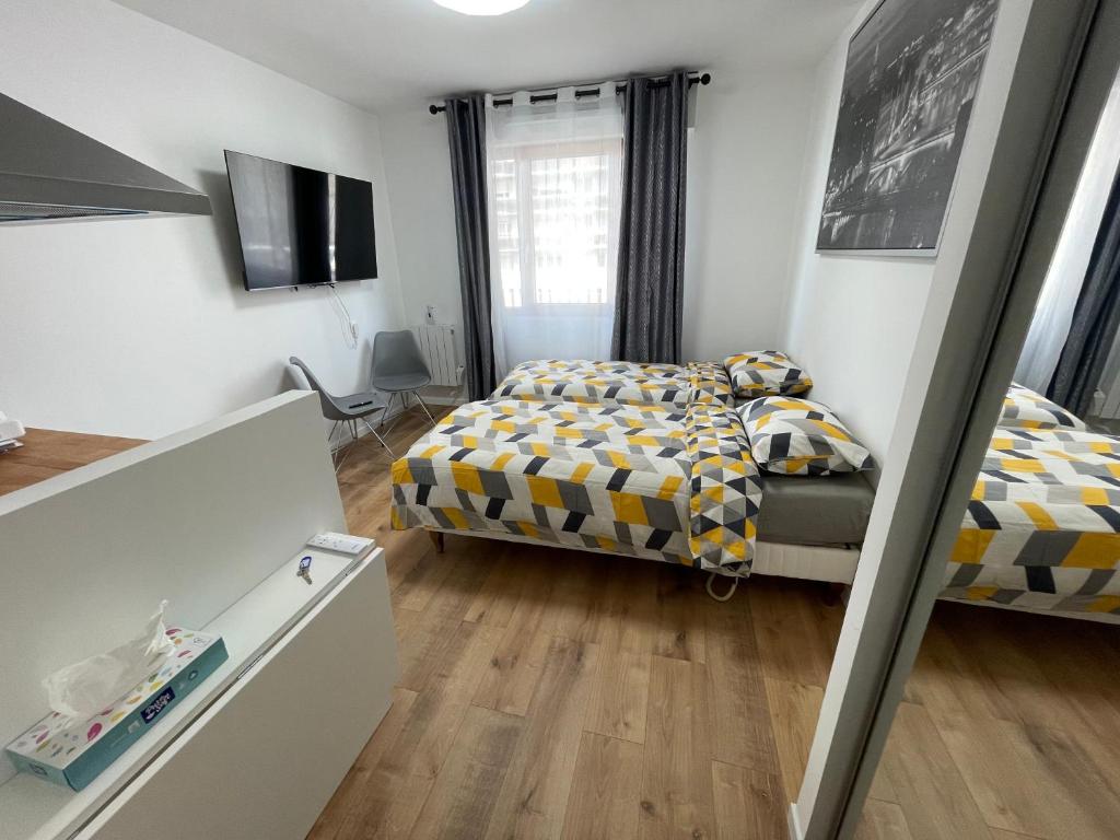 Un dormitorio pequeño con una cama y un televisor. en Appartement au Pied du Metro Mairie de Clichy L13, en Clichy