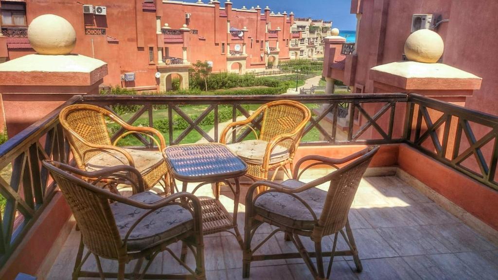 Lazorde Bay Apartment في العلمين: مجموعة من الكراسي والطاولات على الشرفة