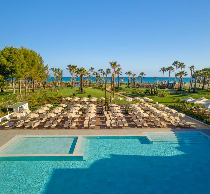 a resort with a pool and chairs and the ocean at Mangia's Himera Resort in Campofelice di Roccella