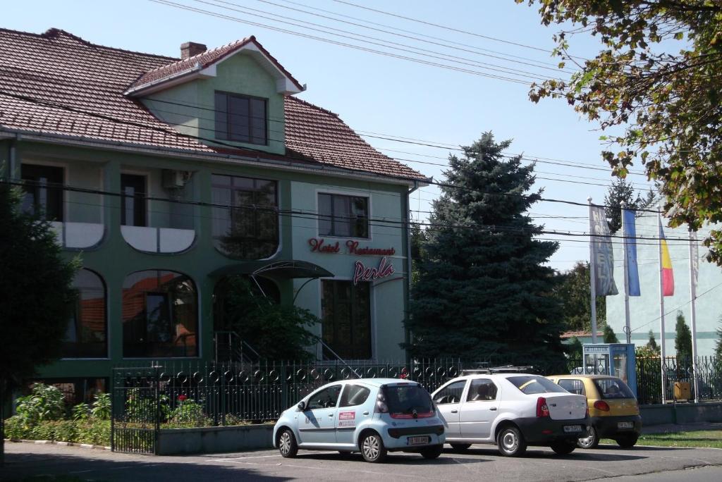 two cars parked in front of a building at Hotel Perla in Satu Mare