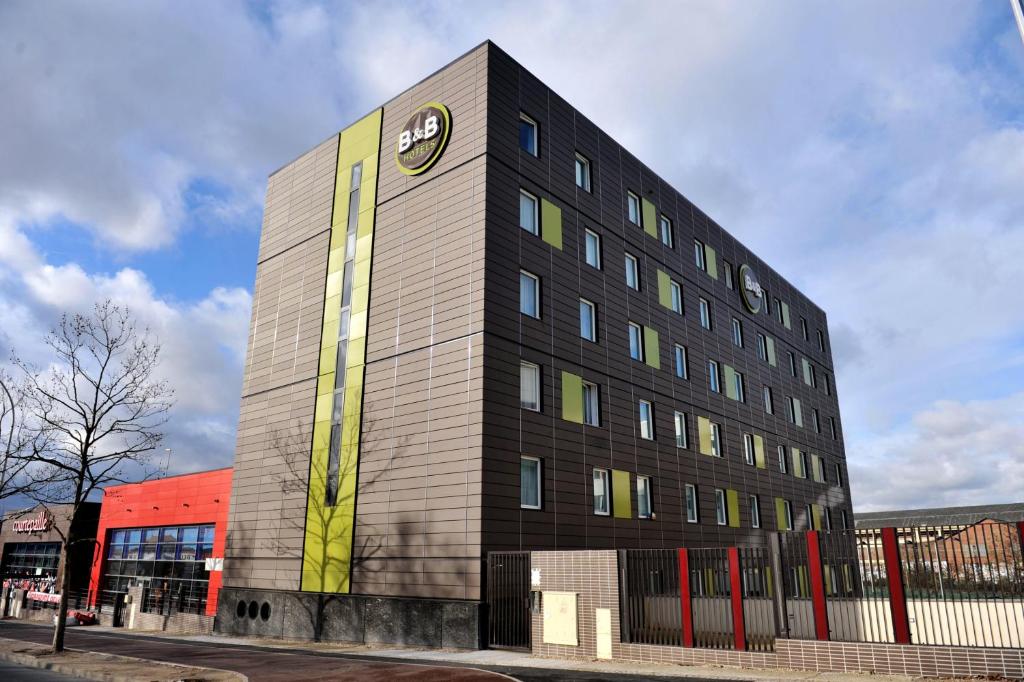 a building with a clock on the side of it at B&B HOTEL Paris Le Bourget in Le Bourget