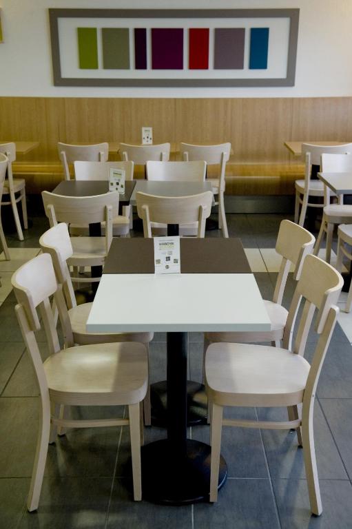 a dining room with white tables and chairs at B&B HOTEL Paris Le Bourget in Le Bourget