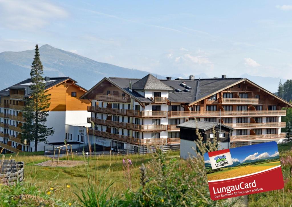 a hotel in the mountains with a sign in the foreground at Das Alpenhaus Katschberg 1640 inkl Lungau Card in Katschberghöhe