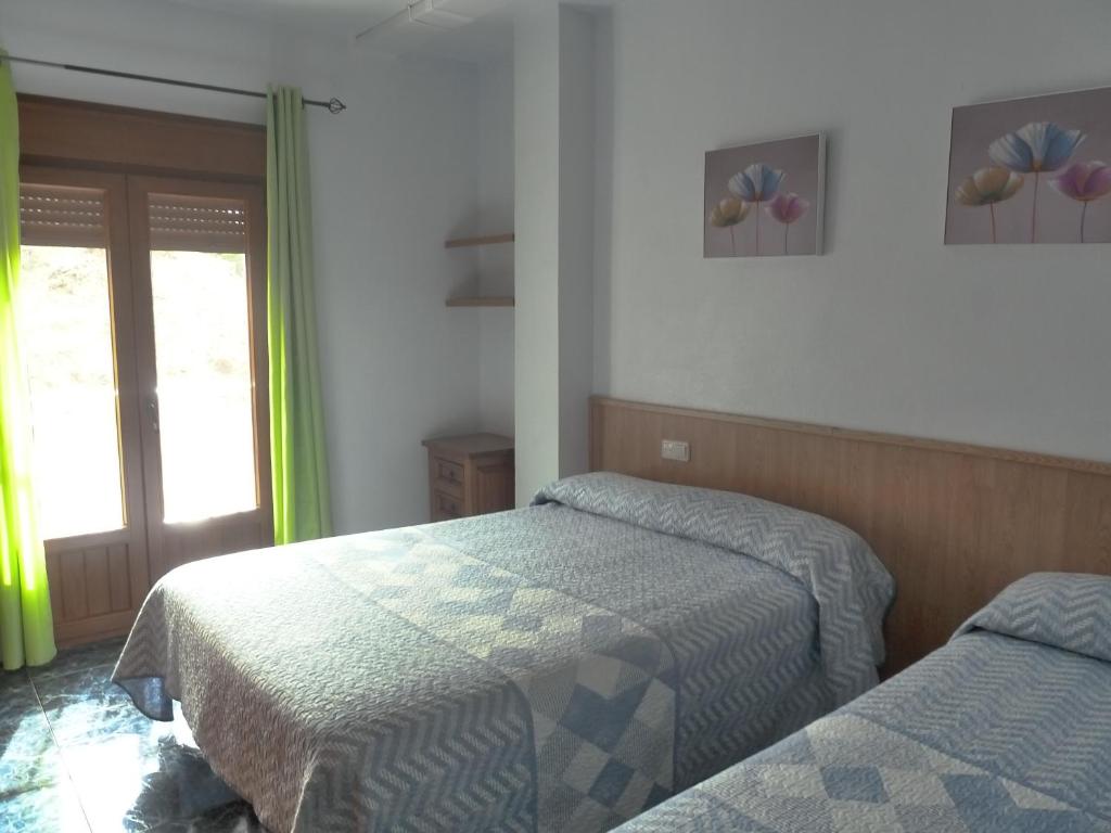 a bedroom with two beds and a window at Apartamentos Casa FERMINA - A 2 horas de las pistas de esquí in Trevélez