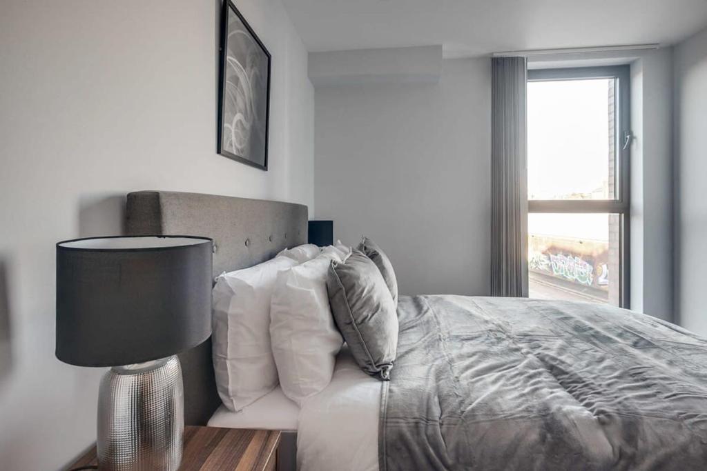 1 dormitorio con 1 cama con lámpara y ventana en Smart 2 Bedroom Flat in the Heart of Birmingham, en Birmingham