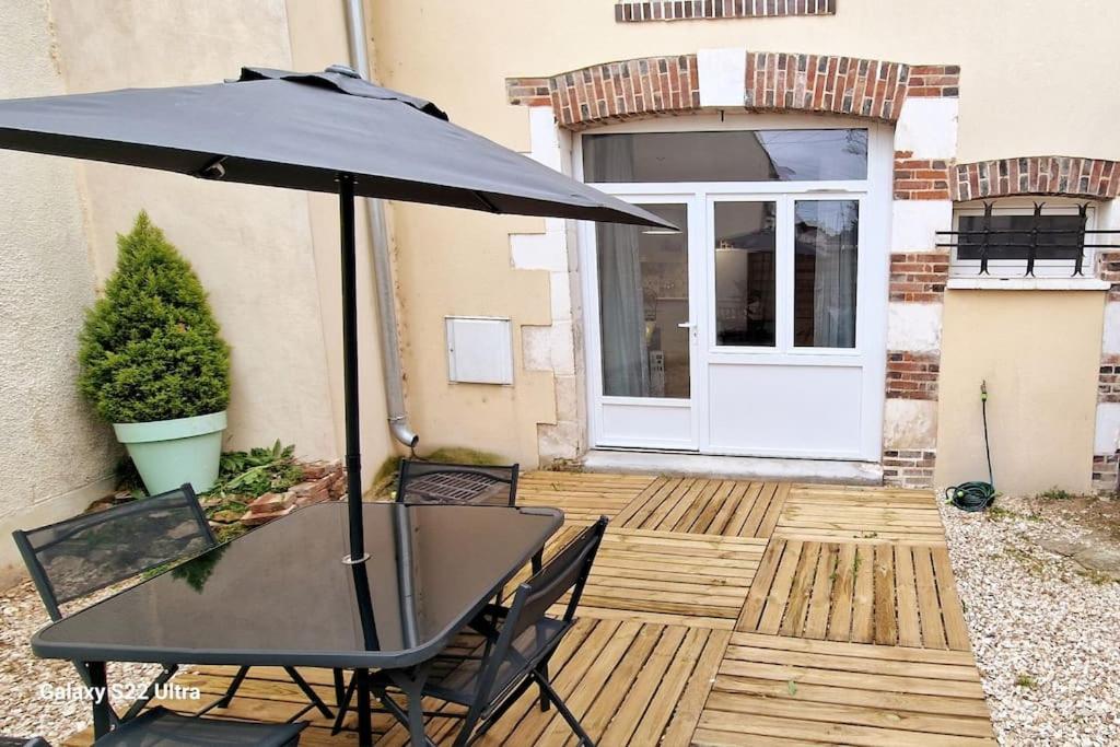 een tafel en stoelen met een parasol op een patio bij LE CHATEL BOURGEOIS in Appoigny