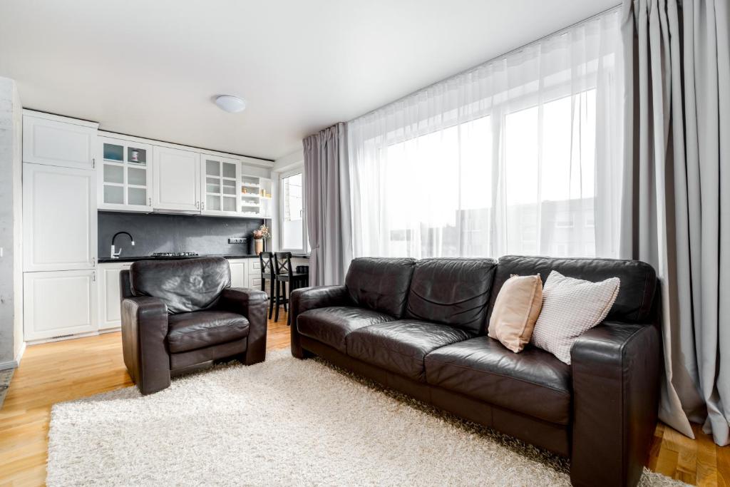 a living room with a leather couch and a chair at Angel House Vilnius, Skroblu 39 in Vilnius